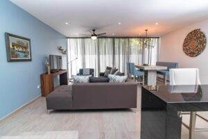 Modern living room interior with sectional sofa, dining area, and blue walls.